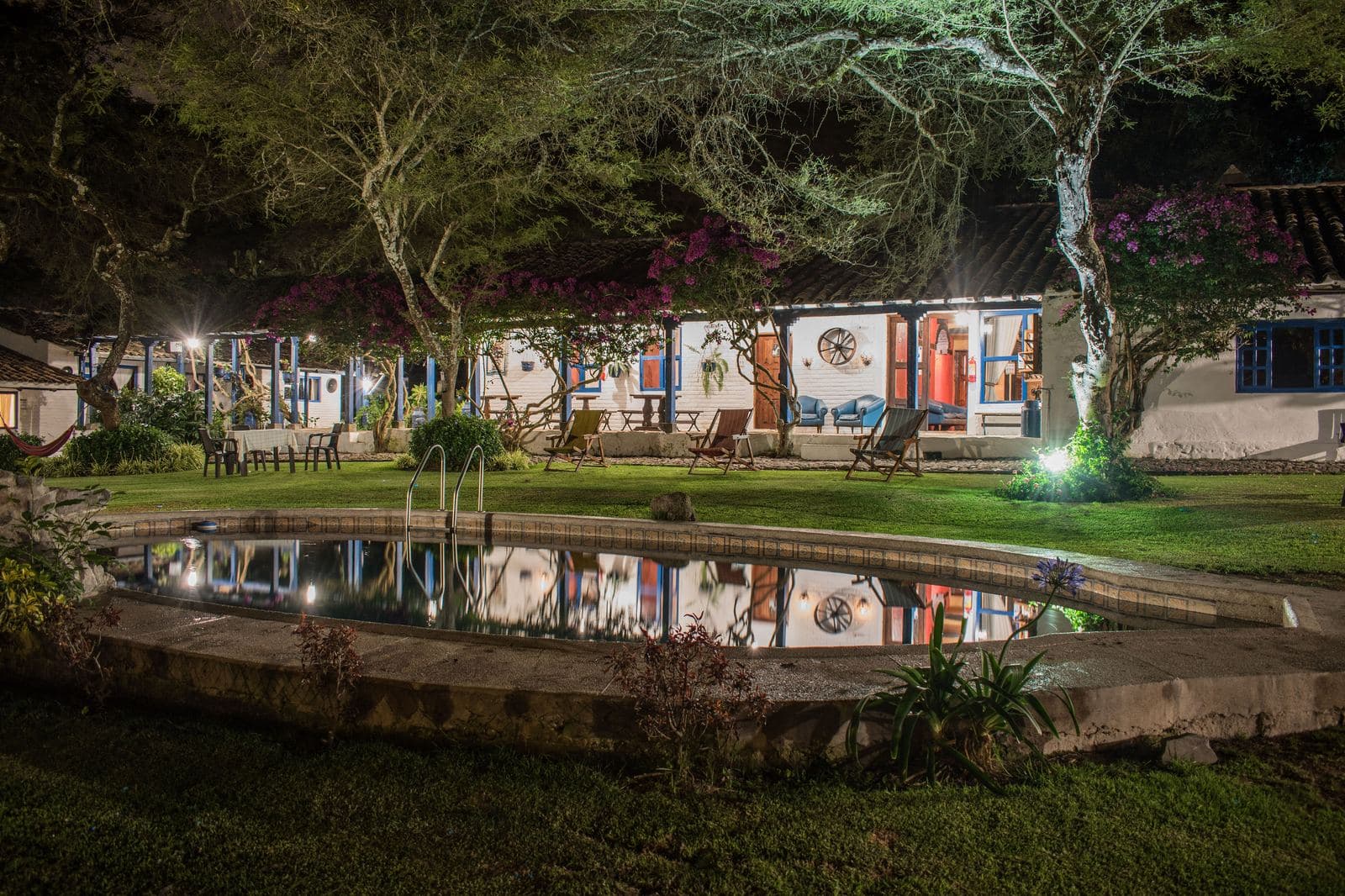 Fotografía nocturna de piscina y jardín de hospedaje